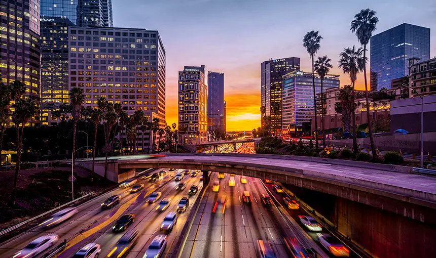 A busy freeway with cars driving on it at sunset.